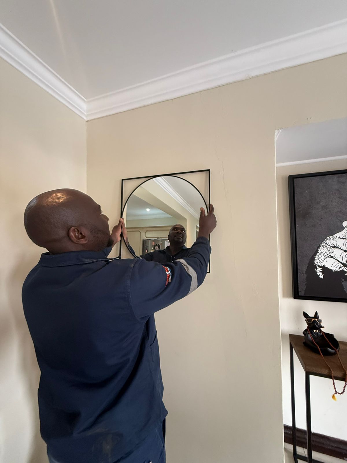 TIQ Group technician levelling an arched framed mirror onto a wall